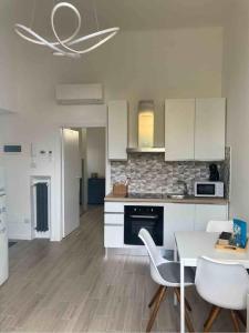 eine Küche mit weißen Schränken und einem Tisch und Stühlen in der Unterkunft Casa Coralli in Pavia