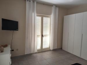 a room with a window with white curtains and a television at Five Street B&B in Nola