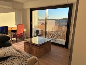 a living room with a glass table and a balcony at chambre avec salle de bain, cuisine, balcon, clim et parking privé ,bordeaux centre Nansouty in Bordeaux