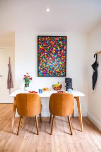 a dining room table with two chairs and a painting at Stylish flat in the heart of Hitchin with free parking in Hitchin