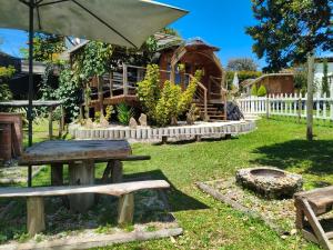 a picnic table and an umbrella in front of a log cabin at Glamping Cabañas Sharmont in Guarne