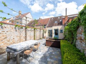 un patio con mesa y sillas junto a una pared de ladrillo en Tuzzetje, en Nieuwpoort