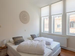 two beds in a white room with two windows at Notre Dame in Nieuwpoort