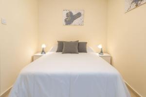a bedroom with a large white bed with two lamps at Triana Home centro ciudad in Murcia +6 photos