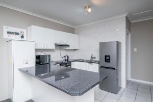 a kitchen with white cabinets and a granite counter top at Prime Executive Apartments 2 in Durbanville