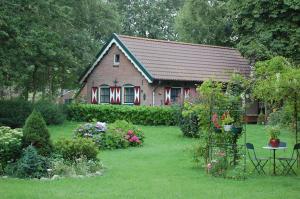 a small house with a yard with flowers and plants at B&B BeZINspiratie in Schuinesloot