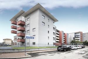 a white building with cars parked in a parking lot at New One Bedroom Apartment in Milan 3 minutes from the metro in San Giuliano Milanese