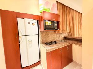 a small kitchen with a white refrigerator and a microwave at Suite exclusiva en Machala in Machala +2 photos
