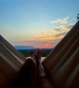een persoon die in een hangmat ligt en naar de zonsondergang kijkt bij Casa Mirante 360 in Cavalcante