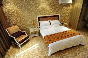 a bedroom with a large bed and a chair at Rose Garden Hotel in Riyadh
