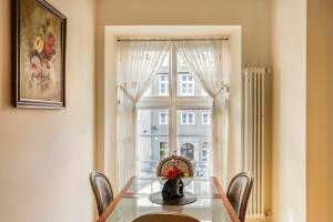 a dining room table with chairs and a window at Cosmo - Old Money Apartment in Gdańsk