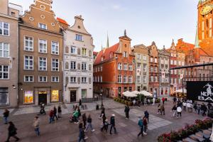 a group of people walking around a street with buildings at Cosmo - Old Money Apartment in Gdańsk