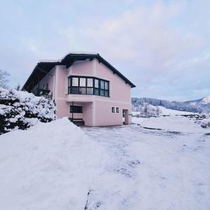 ein rosa Haus mit Schnee davor in der Unterkunft Ferienwohnung Blick ins Grüne in Rossleithen
