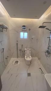 a white bathroom with a toilet and a sink at بلو بتش 1 للشقق المخدومة Blue Beach 1 Apartments in Al Qunfudhah