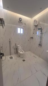 a white bathroom with a toilet and a window at بلو بتش 1 للشقق المخدومة Blue Beach 1 Apartments in Al Qunfudhah +25 photos