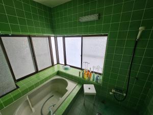 a green tiled bathroom with a tub and windows at Mogamigun - House - Vacation STAY 20213 in Shinjo