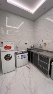 a white kitchen with a sink and a refrigerator at بلو بتش 1 للشقق المخدومة Blue Beach 1 Apartments in Al Qunfudhah