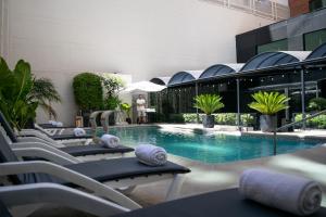 a pool with chaise lounge chairs next to a building at Regal Pacific Puerto Madero in Buenos Aires