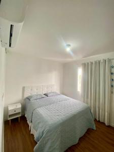 a white bedroom with a bed and a window at Apê moderno com Ar, Wi-Fi, máquina de lavar, garagem e portaria 24h- completo e confortável! in Caruaru