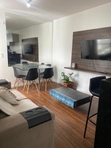 a living room with a tv and a table and chairs at Apê moderno com Ar, Wi-Fi, máquina de lavar, garagem e portaria 24h- completo e confortável! in Caruaru +11 photos