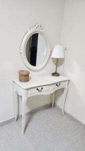 a white dressing table with a mirror and a lamp at צימר החורש in Dāliyat el Karmil