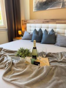 a bottle of wine and two glasses on a bed at Fewo Freya in der Ostseeresidenz Gendarm in Wischuer
