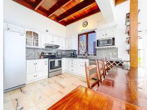 a kitchen with white cabinets and a wooden table at Villa Leones Breathtaking Views and Authentic Charm in Oyster Pond +42 photos