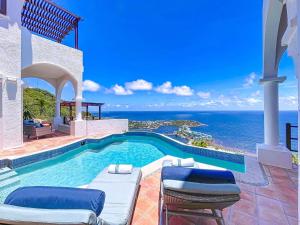 a house with a swimming pool with a view of the ocean at Villa Leones Breathtaking Views and Authentic Charm in Oyster Pond