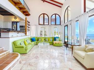 a living room with green couches and windows at Villa Leones Breathtaking Views and Authentic Charm in Oyster Pond