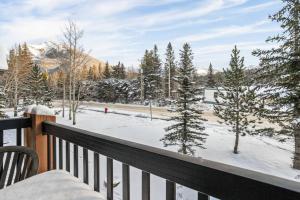 einen Balkon mit Blick auf schneebedeckte Bäume in der Unterkunft Bears Den 2BR Getaway with Hot Tub, BBQ Near DT in Dead Man's Flats