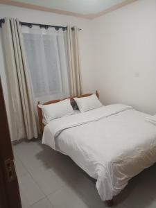 a bedroom with a bed with white sheets and a window at 1 bedroom BNB Meru in Meru