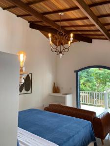 a bedroom with a blue bed and a chandelier at Villa Maree Bahia in Marau