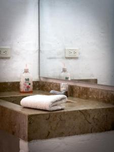 a bathroom sink with a towel and a mirror at The Blue House Hostel Santa Marta in Santa Marta