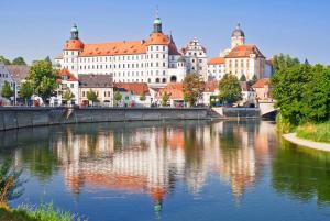 a river in front of a large building at Ferienwohnung im Bortenmacherhaus in Neuburg an der Donau