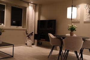 a living room with a table and chairs and a television at Arctic City Suites 2 in Kirkenes
