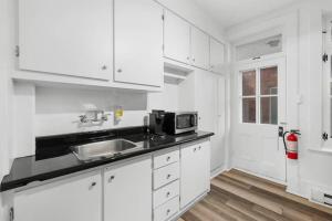 Una cocina blanca con fregadero y microondas. en Suite Jardin, en Quebec