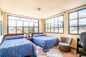 a bedroom with two beds and a chair and windows at Finca Moralia in Cajicá