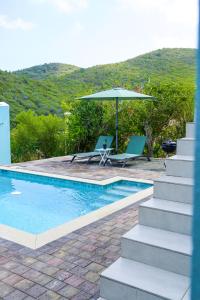 una piscina con dos sillas y una sombrilla en Beach House, Tranquil Santirome Studio 2, en Westpunt