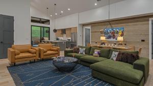 a living room with green couches and a kitchen at Friesian Chalet in Steamboat Springs