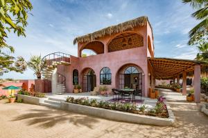 una grande casa rosa con un tavolo davanti di Casa Todos by Boutique A Baja Oasis a Todos los Santos