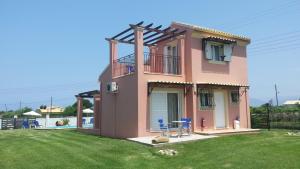 een roze huis met blauwe stoelen in een tuin bij Villa Filia in Almiros strand