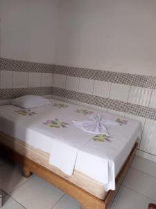 a bed with white sheets and flowers on it at Hotel Contorno in Santa Inês +2 photos