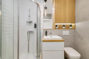 a bathroom with a shower and a sink and a toilet at Sen Krasnala by FuzjaAparts in Wrocław +22 photos