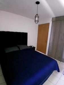 a bedroom with a blue bed and a brown door at Departamento Ganges in León