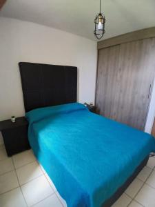 a bed with a blue bedspread in a room at Departamento Ganges in León