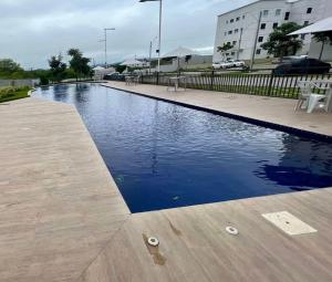 a swimming pool with a wooden deck and blue water at Apê aconchegante e climatizado - Villa Kennidy in Caruaru