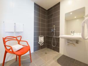 a bathroom with a orange chair and a sink at Hôtel Confort La Rochelle Centre les Minimes in La Rochelle
