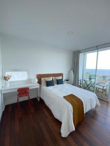 Un dormitorio blanco con una cama grande y un escritorio. en Marea Alta, en La Caleta