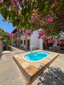 - une piscine dans l'arrière-cour d'une maison ornée de fleurs roses dans l'établissement Vila Bella Barra Grande, à Barra Grande