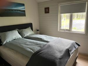 a bed in a bedroom with a window and a bedspread at Árbakki Horsecenter cottage in Hella